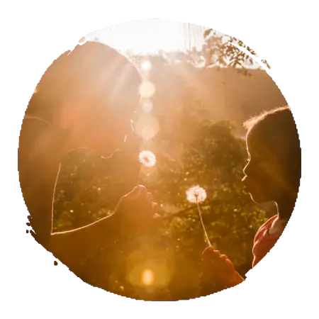 2 jeunes filles qui soufflent sur des graines de pissenlit dans le rayon du soleil