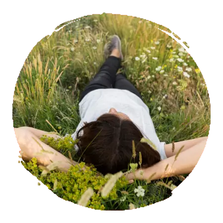 femme allongée dans l'herbe, les bras croisés derrière la tête